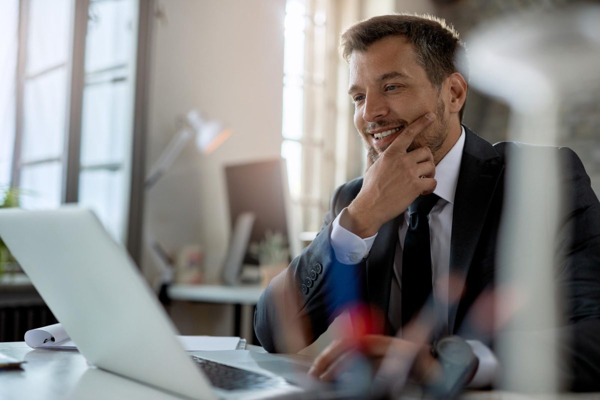 hombre-negocios-adulto-medio-sonriente-que-usa-computadora-mientras-trabaja-escritorio-oficina